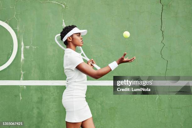 shot of an attractive young woman warming up and getting ready to play tennis outside - tennis stock pictures, royalty-free photos & images