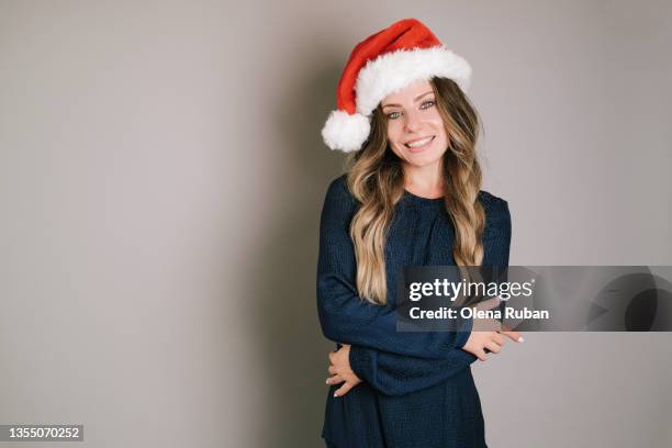 young woman in xmas hat embracing herself. - cappello da babbo natale foto e immagini stock