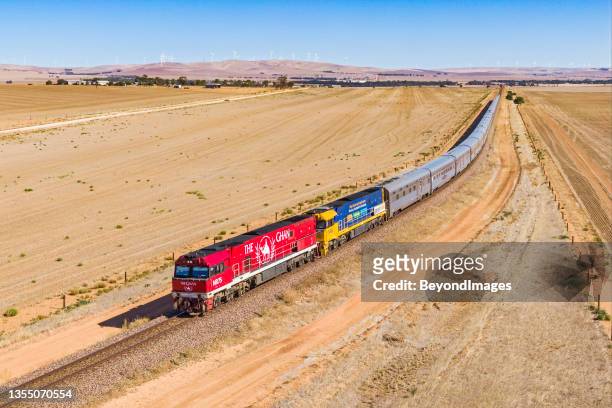 aerial view of the legendary ghan tourist train with red & blue engines in outback south australia with wind turbines - darwin australia aerial stock pictures, royalty-free photos & images