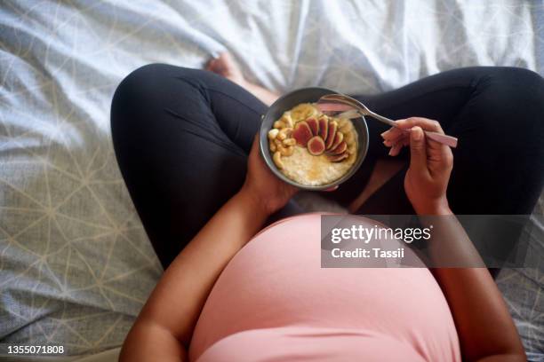 high angle shot of an unrecognizable pregnant woman having a healthy breakfast while sitting on her bed - pregnancy healthy eating stock pictures, royalty-free photos & images