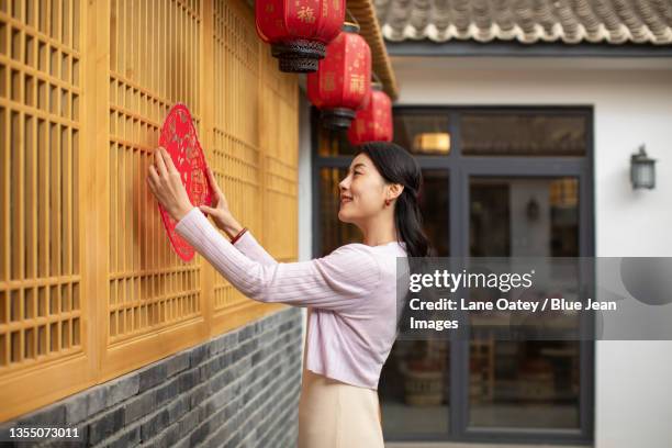 happy young woman decorating house for chinese new year - woman red lantern stock pictures, royalty-free photos & images