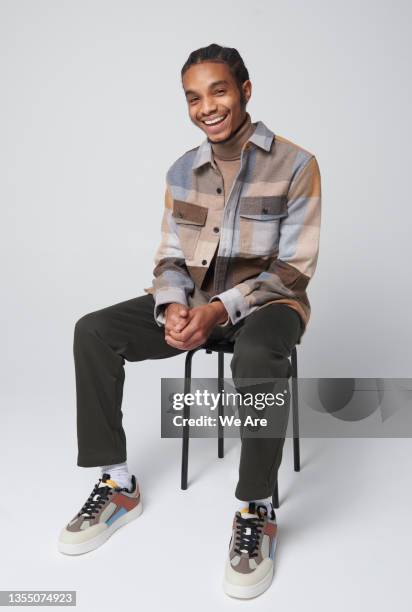 studio portrait of young fashionable man - mensch freistellen sitzen ganzkörper stock-fotos und bilder