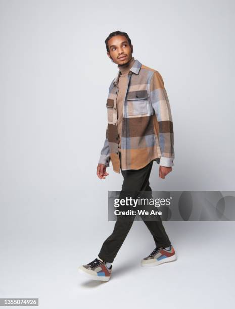 fashionable gen z man walking and looking up - walking stock pictures, royalty-free photos & images