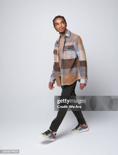 fashionable gen z man walking and looking up - black man walking studio stock pictures, royalty-free photos & images
