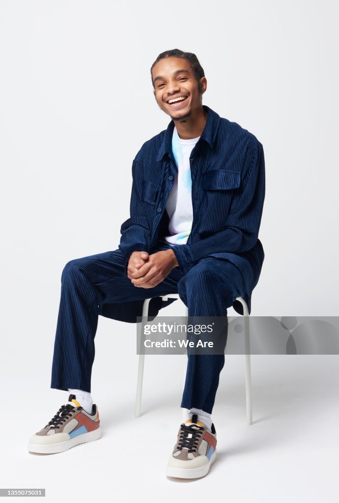 Portrait of young man sitting on stool in studio