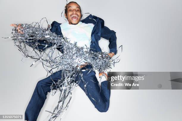 young fashionable man celebrating with silver streamers - blitze freisteller stock-fotos und bilder