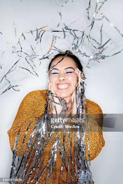 portrait of woman celebrating with silver party streamers - tinsel stock pictures, royalty-free photos & images