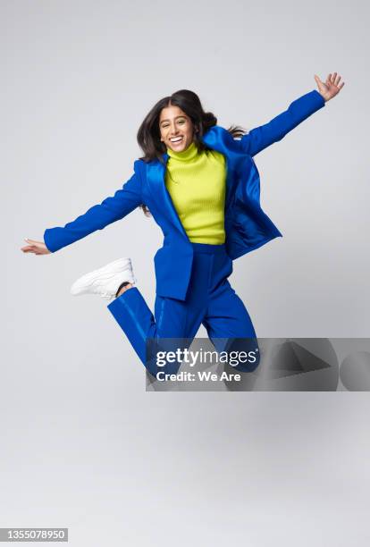 smartly dressed gen z woman jumping - gelber anzug stock-fotos und bilder