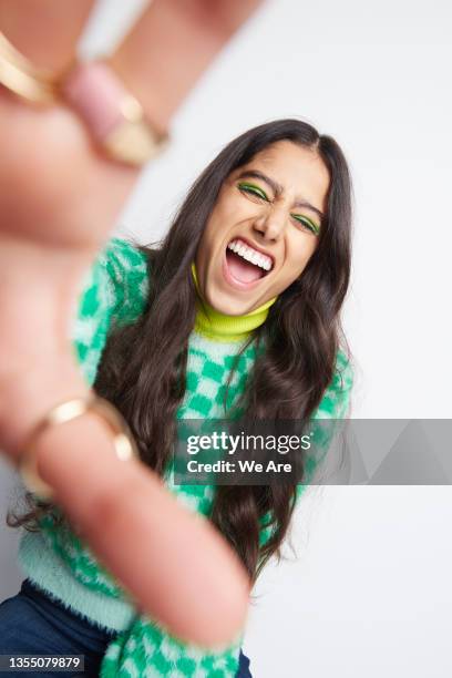 young woman reaching towards camera and laughing - woman reaching hands towards camera stock pictures, royalty-free photos & images