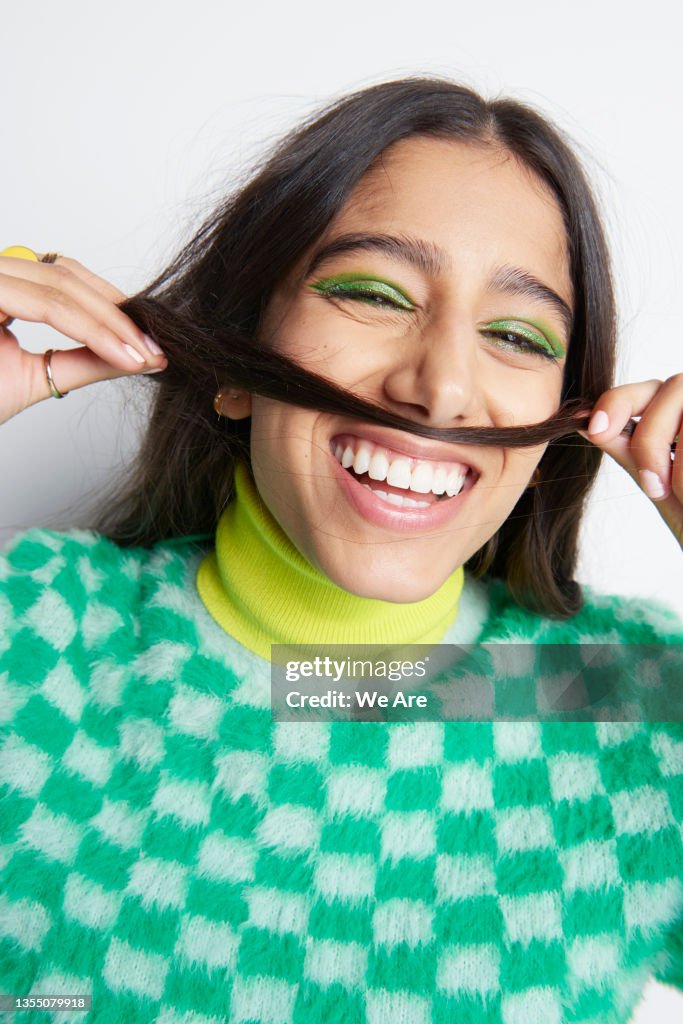Young woman playfully holding hair as a moustache