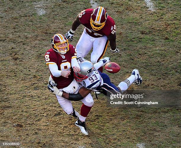 Rex Grossman of the Washington Redskins passes as he is hit by Andre Carter of the New England Patriots at FedEx Field on December 11, 2011 in...