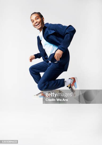 young man in suit jumping in studio - suit men ストックフォトと画像
