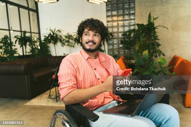 オフィスレセプションルームでの複合レースエグゼクティブアソシエイツミーティングと現代オフィスコワーキングの場所の座り込みエリアでのアイデア交換。車椅子の障害のあるインドの� - man in wheelchair ストックフォトと画像