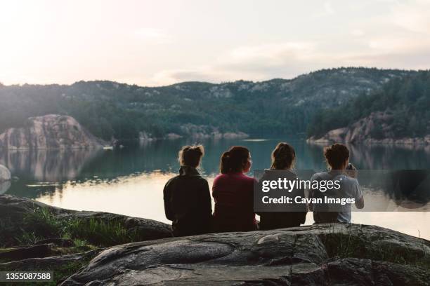 four young women are sitting and relaxing by the lake at dusk - ヒューロン湖 ストックフォトと画像