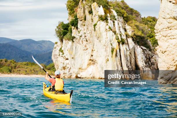 woman kayaking beside abel tasman national park cliffs - tasman district new zealand stock pictures, royalty-free photos & images