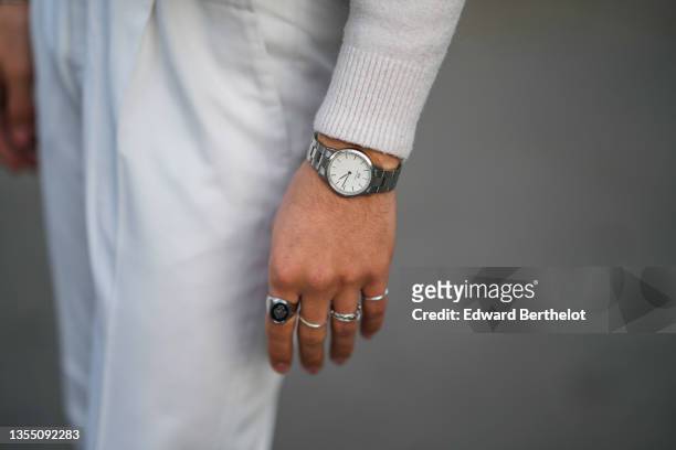 Marco Capaccioli wears a white cashmere turtleneck pullover from Falconeri, a silver watch from Daniel Wellington, silver rings, white carrot suit...