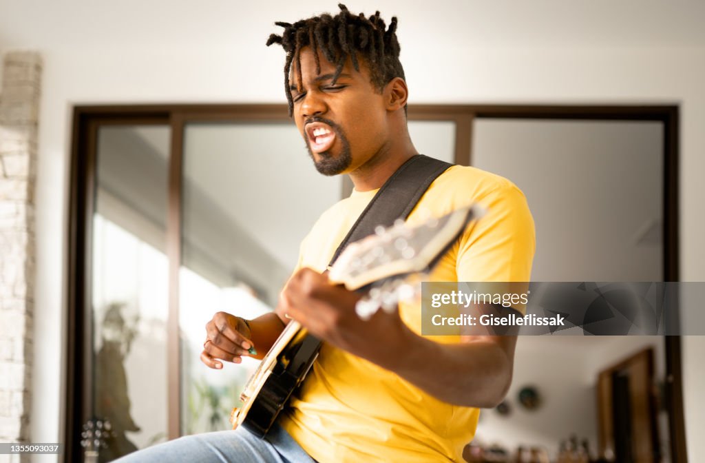 Junger Mann, der während einer Bandprobe eine E-Gitarre spielt