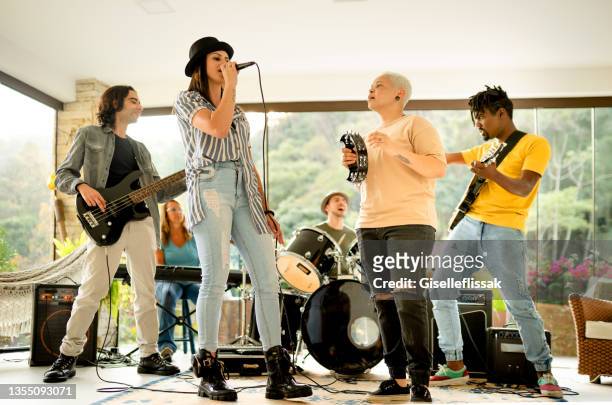 banda joven diversa tocando una canción juntos en un estudio de música casero - performance group fotografías e imágenes de stock