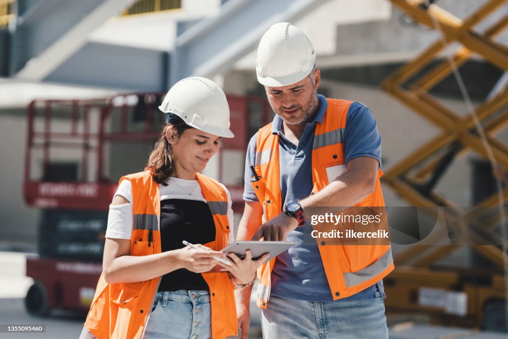 Civil Engineers Checking Works According To Project Using Digital Tablet At Construction Site