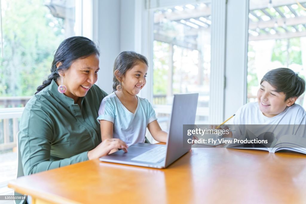 Mom helping elementary age girl with e-learning video conference call