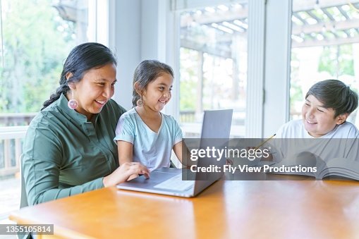 Mom helping elementary age girl with e-learning video conference call Mom helping elementary age girl with e-learning video conference call