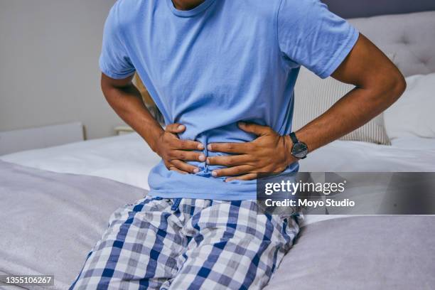 shot of an unrecognizable man suffering from a stomachache at home - irritable bowel syndrome stock pictures, royalty-free photos & images