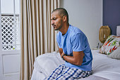 Shot of a young man suffering from a stomachache at home