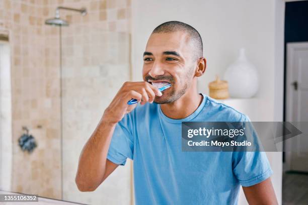 shot of a young man brushing his teeth in a bathroom at home - brushing teeth stock pictures, royalty-free photos & images