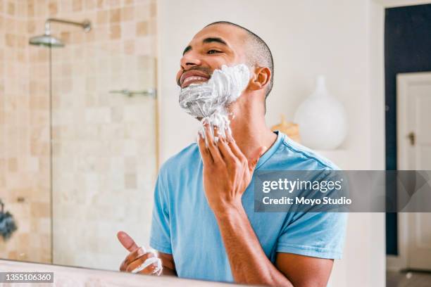 shot of a young man applying shaving cream to his face in a bathroom at home - shaved stockfoto's en -beelden