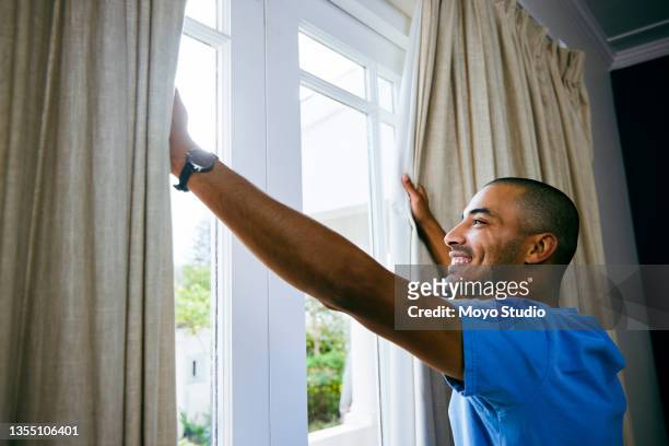 shot of a young man opening up the curtains in a bedroom at home - drapery stock pictures, royalty-free photos & images