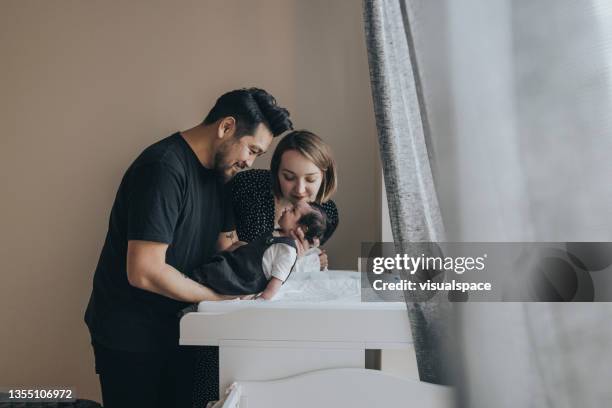 young family changing newborn baby diapers - changing diaper imagens e fotografias de stock