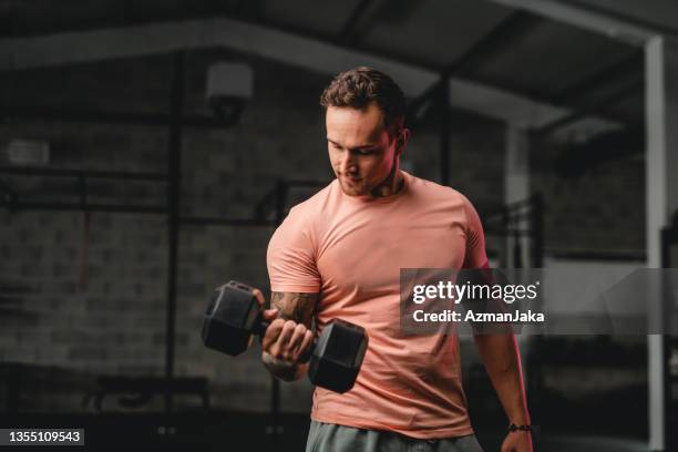 late 20s male athlete working out with dumbbell - dumbbell stock pictures, royalty-free photos & images