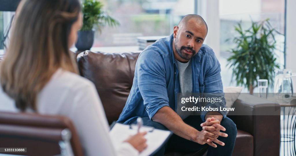 Cropped shot of a handsome young man looking thoughtful while sitting in session with his female therapist