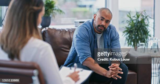 cropped shot of a handsome young man looking thoughtful while sitting in session with his female therapist - psychotherapy stock pictures, royalty-free photos & images