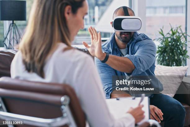 cropped shot of a young man wearing a vr headset while sitting in session with his female therapist - virtual bildbanksfoton och bilder