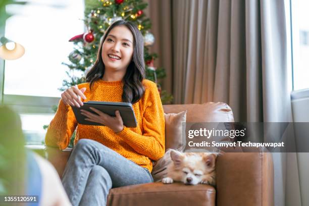 christmas holiday vacation,asian female friend spending time conversation together at home,asian female sitting on sofa couch with old senior dog talking with friend connect relation with fun and joyful at apartment - real time stock pictures, royalty-free photos & images