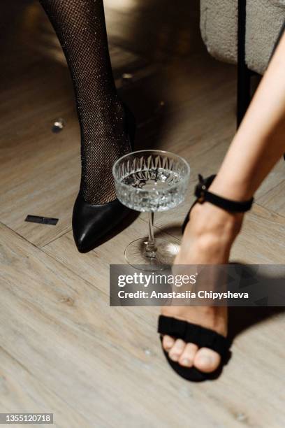 glass of water on the floor near the foot - womens beautiful feet stock-fotos und bilder