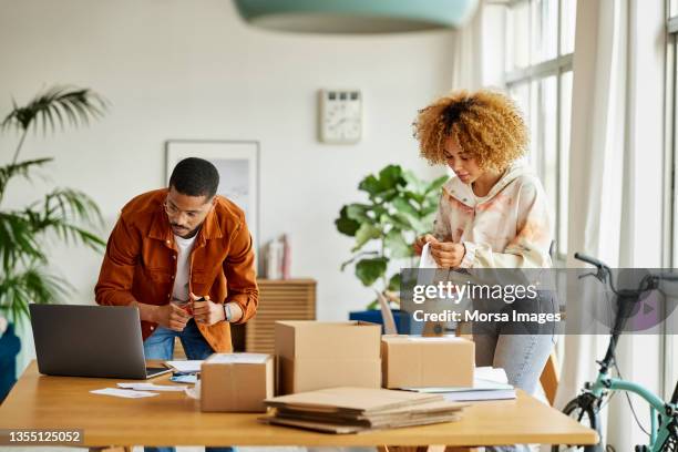 male and female colleagues working at home office - doing a favor - fotografias e filmes do acervo