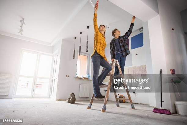 mother and son painting wall at home - verbouwen stockfoto's en -beelden