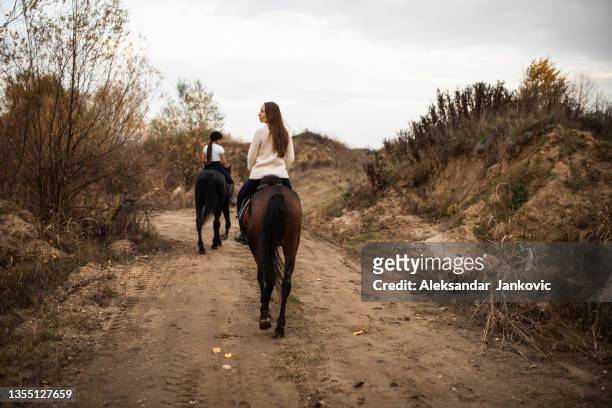 zwei junge frauen reiten auf dem land - horseback riding stock-fotos und bilder