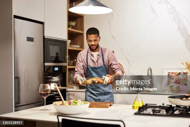 young man holding tray with freshly baked meat - homme cuisine photos et images de collection
