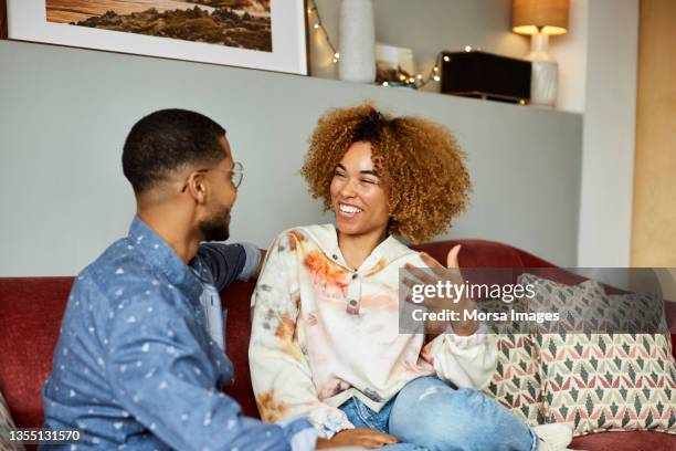 cheerful woman talking with boyfriend in apartment - young couple watching tv stock pictures, royalty-free photos & images