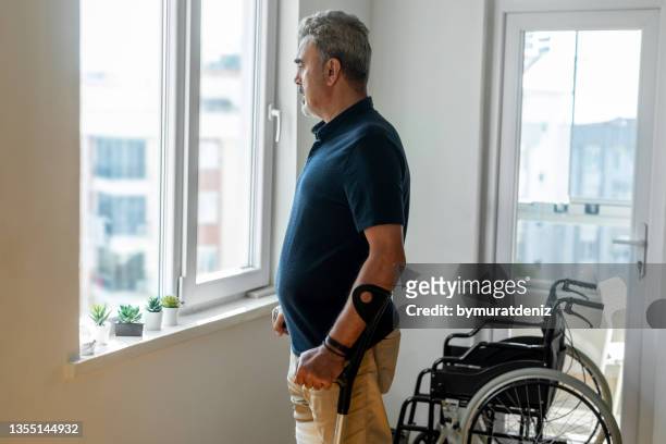 injured man on crutches looking out - rudeness stock pictures, royalty-free photos & images