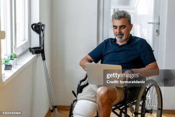 senior man with broken leg on wheelchair - misfortune stockfoto's en -beelden