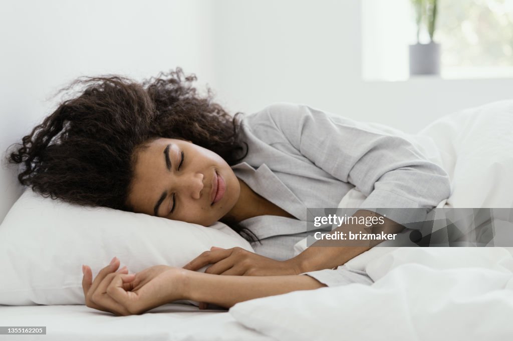 Mujer afroamericana durmiendo en la cama en casa