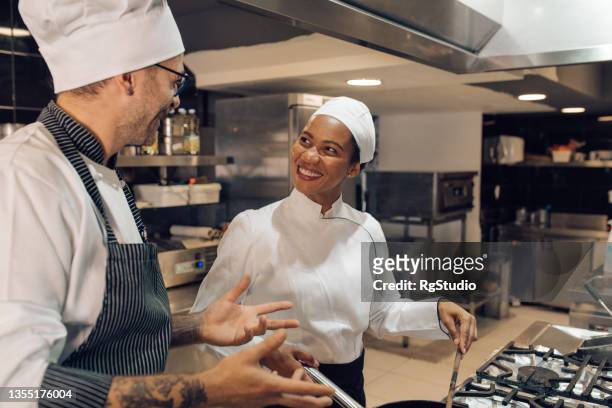 junge frau lernt vom koch, wie man in der restaurantküche kocht - kochlehrling stock-fotos und bilder