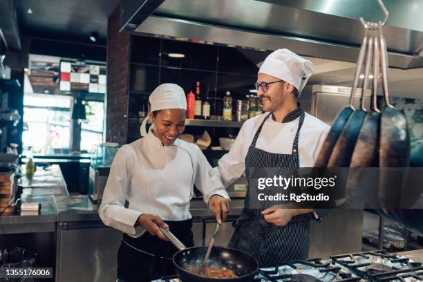 koch und sein auszubildender kochen gemeinsam - kochlehrling stock-fotos und bilder