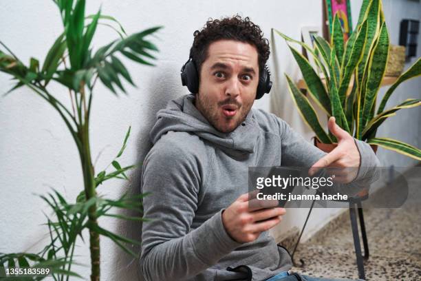 man watching a movie pointing to his phone with an amazed expression. - südeuropa stock-fotos und bilder