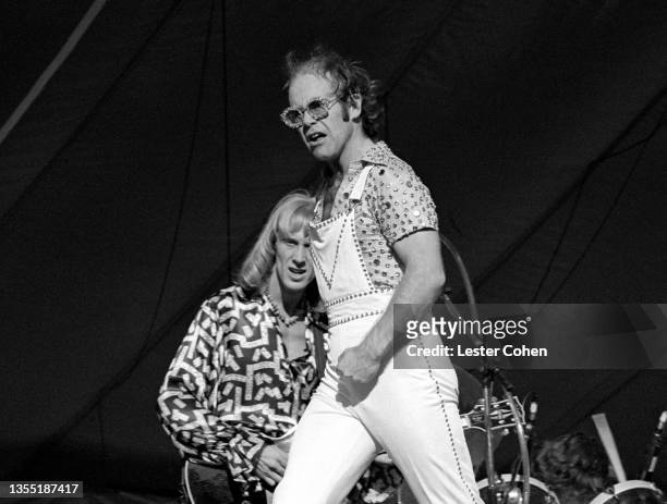 English singer, pianist and composer Elton John walks on stage as Scottish rock guitarist and vocalist Davey Johnstone plays his guitar during the...