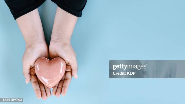 healthcare, love, charitable donations and organ donation concepts. woman hands is holding heart shape with copy space on blue isolated background. - almosen stock-fotos und bilder